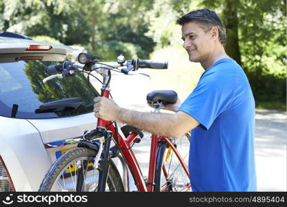 Mature Male Cyclist Taking Mountain Bike From Rack On Car