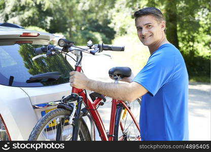 Mature Male Cyclist Taking Mountain Bike From Rack On Car