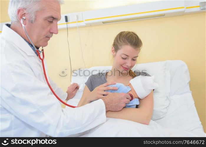 mature male doctor examining baby girl with mother watching