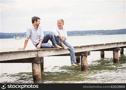 Mature male friends relaxing on pier
