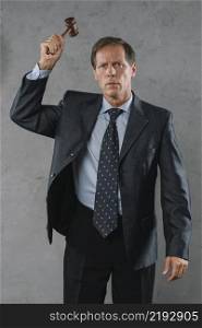 mature male lawyer hitting with gavel against gray textured background