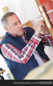 mature male locksmith fixing door handle at a home
