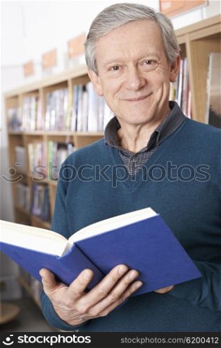 Mature Male Student Reading Book In Library