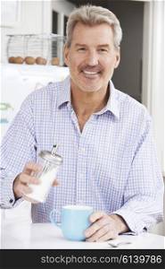 Mature Man Adding Sugar to Cup Of Coffee