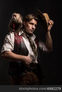 Mature man adventurer in costume of traveler with his monkey companion holding old gun on black background