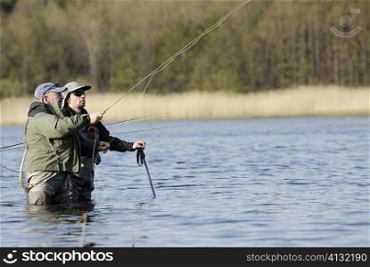 Mature man and a mid adult man fishing in the river