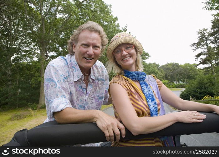 Mature man and a mid adult woman in a convertible car and smiling