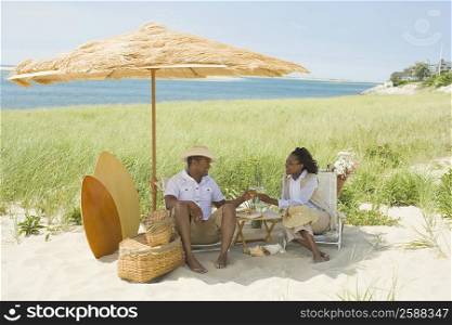 Mature man and a mid adult woman toasting with wine glasses on the beach