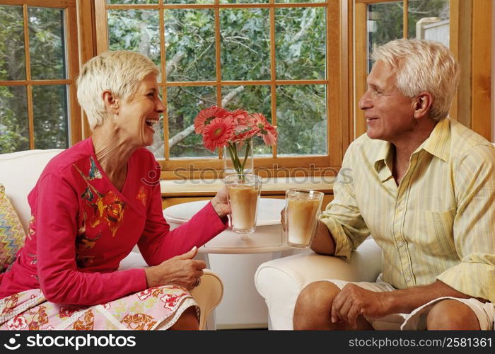 mature man and a senior woman sitting on chairs and holding mugs of coffee