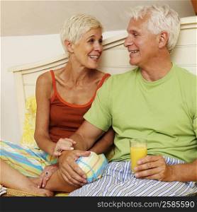 mature man and a senior woman sitting on the bed and smiling