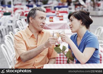 Mature man and a young woman toasting at a sidewalk cafe