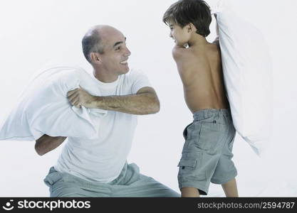 Mature man and his son having a pillow fight
