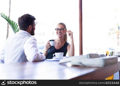 Mature man and woman, sitting outside cafe, drinking coffee, face to face, smiling