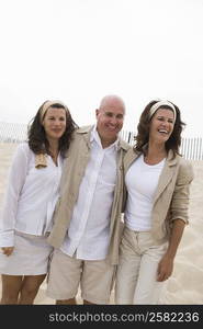 Mature man arm around with two mature women on the beach