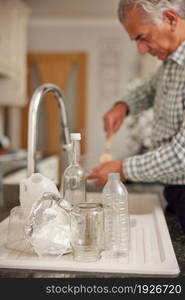 Mature Man At Home In Kitchen Washing Used Packaging Before Recycling