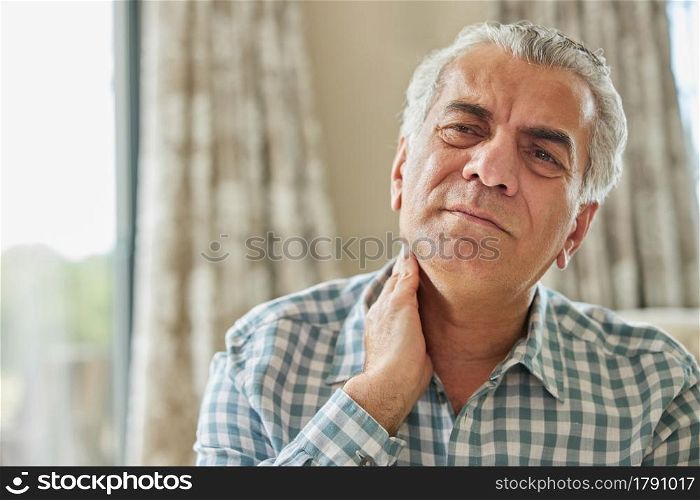 Mature Man At Home Suffering From Muscle Pain Or Ache In Neck