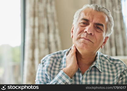 Mature Man At Home Suffering From Muscle Pain Or Ache In Neck