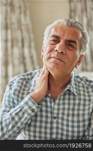 Mature Man At Home Suffering From Muscle Pain Or Ache In Neck
