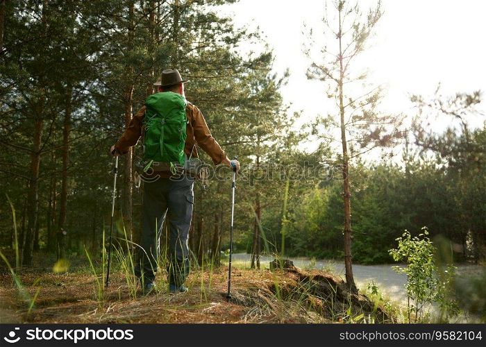 Mature man backpacker enjoying life walking in woods and enjoying beautiful environment scene. Trekking to explore outdoors on pension concept. Mature man backpacker enjoying life trekking to explore outdoors