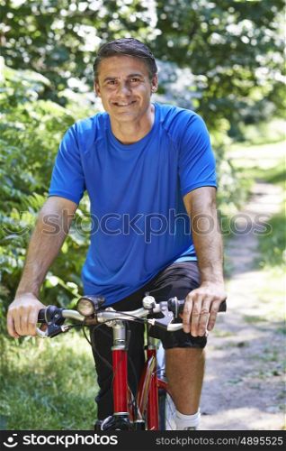 Mature Man Cycling Along Path In Countryside