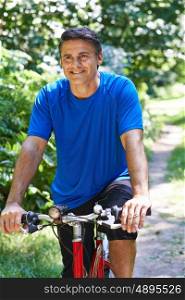 Mature Man Cycling Along Path In Countryside