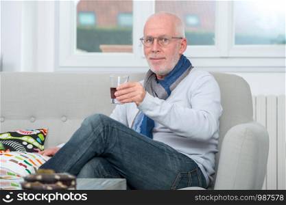 mature man drinking a glass of alcohol at home