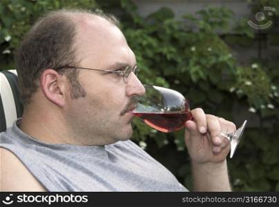 Mature man drinking a glass of rose in the garden
