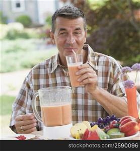 Mature man drinking juice with a drinking straw