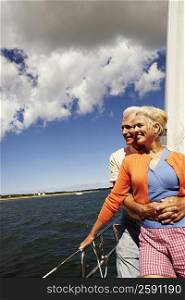 Mature man embracing a mature woman from behind in a sailboat and smiling