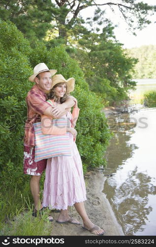 Mature man embracing a mature woman from behind near a pond