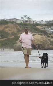 Mature man exercising dog on beach