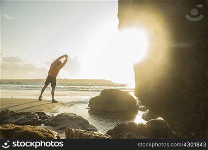 Mature man exercising on beach, looking out to sea