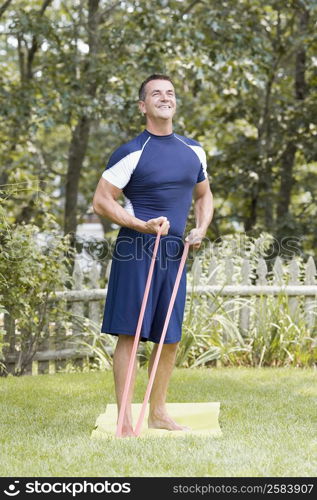 Mature man exercising with resistance band in a lawn