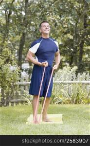 Mature man exercising with resistance band in a lawn