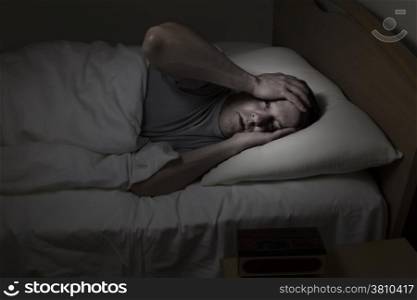 Mature man, eyes wide open with both hands on his forehead, cannot sleep at night from insomnia