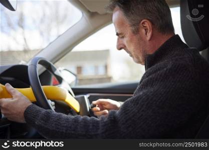 Mature Man Fitting Manual Steering Wheel Lock In Car