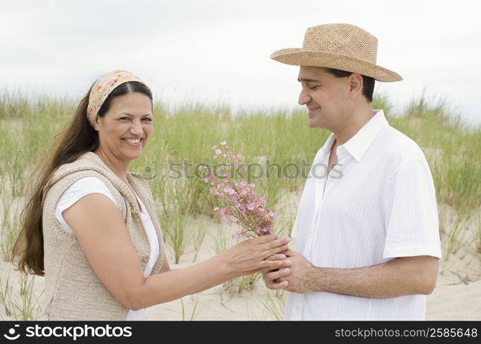 Mature man giving flowers to a mature woman on the beach