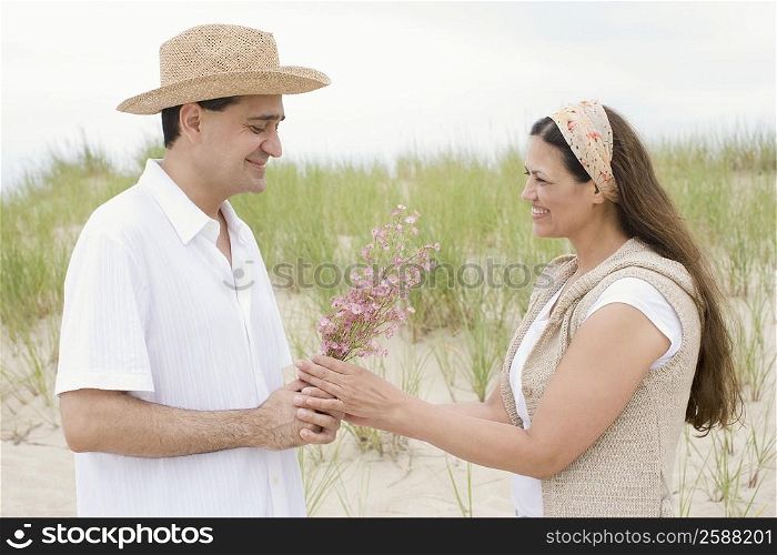 Mature man giving flowers to a mature woman on the beach