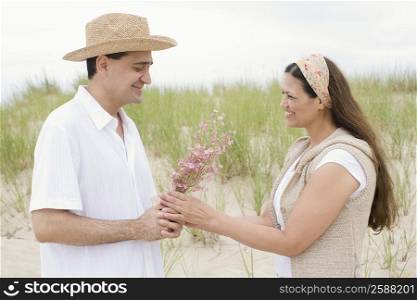 Mature man giving flowers to a mature woman on the beach
