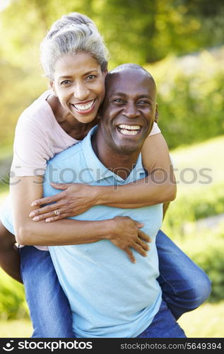 Mature Man Giving Woman Piggyback In Countryside