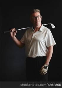 Mature man golfer wearing a white shirt and hold a iron golf club on his shoulder - studio shot, black background