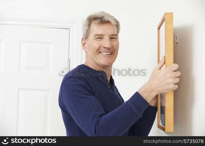 Mature Man Hanging Picture On Wall