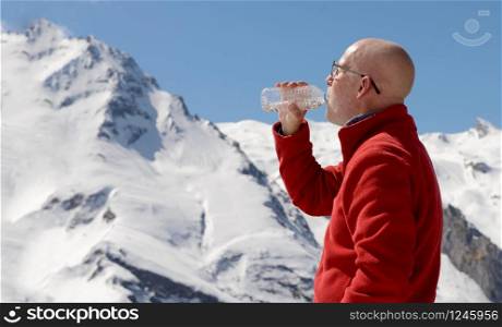 mature man hiker drinking water in mountain