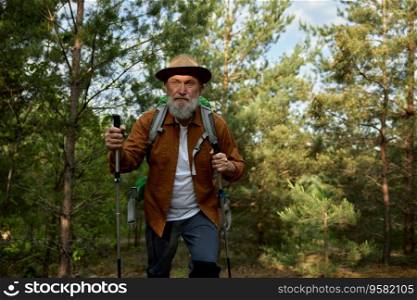 Mature man hiking and exploring forest nature enjoying cardio endurance. Workout adventure on retirement concept. Mature man hiking and exploring forest nature enjoying cardio endurance