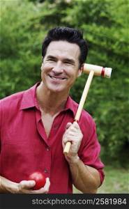 Mature man holding a croquet mallet and a ball