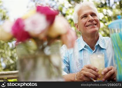 Mature man holding a glass of juice and smiling