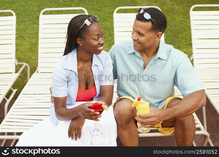 Mature man holding a glass of juice with a mid adult woman holding a martini glass