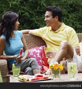 Mature man holding a glass of lemonade with a mature woman holding a slice of water melon beside him