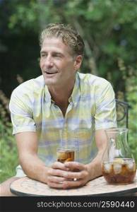 Mature man holding a glass of soda and smiling