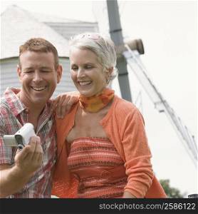 Mature man holding a home video camera with a mature woman smiling beside him